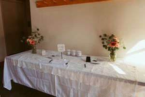 Simple white reception table with floral centerpieces and place settings.