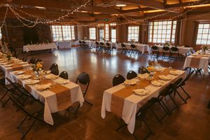 Wedding reception venue with elegant table settings and string lights in a rustic wooden interior.