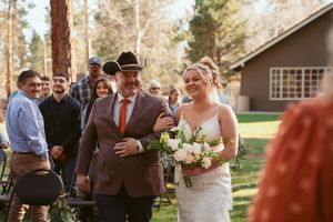 Outdoor wedding ceremony in a rustic mountain setting with pine trees in the background.