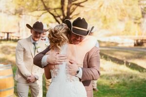 Emotional wedding moment captured during an outdoor autumn ceremony with western-style attire.