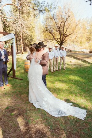 Elegant outdoor wedding ceremony with a stunning lace-train bridal gown and western-themed wedding party.
