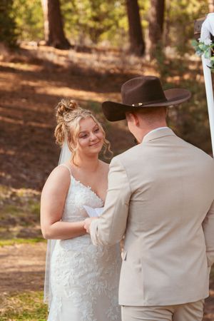 Intimate moment between bride and groom during outdoor forest wedding ceremony.