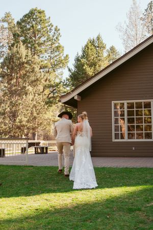 Couple standing outside brown wooden building during forest wedding.