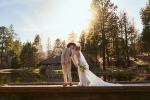 Romantic sunset portrait of newlyweds on wooden dock by forest lake.