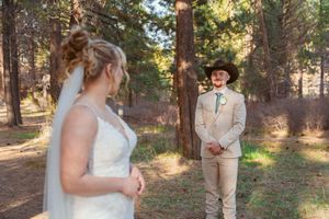 A romantic wedding moment captured in a sun-dappled forest setting.