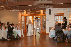 A reception venue decorated with string lights as guests watch a celebratory dance performance.