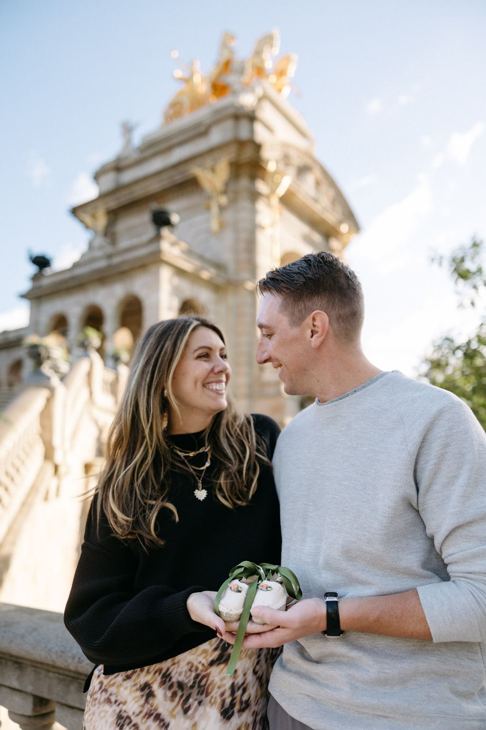 Intimate moment shared between couple near classical architecture on sunny day.