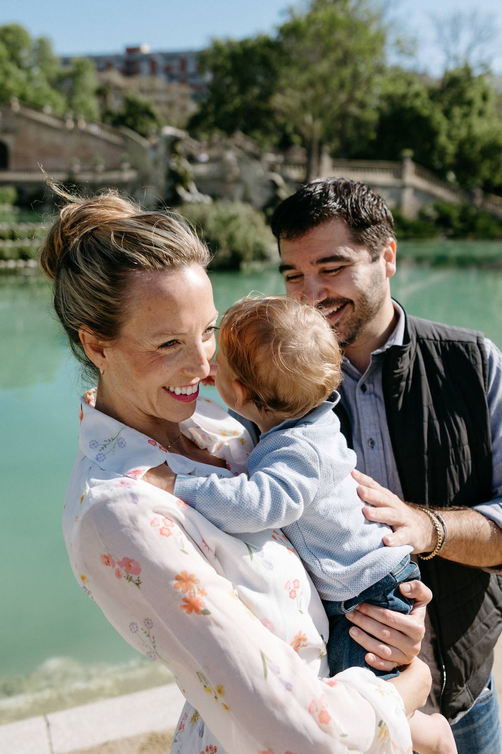 Family shares joyful moment together by waterfront on sunny day.