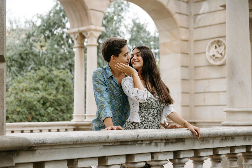 Intimate moment shared under ornate stone archway in European architectural setting.