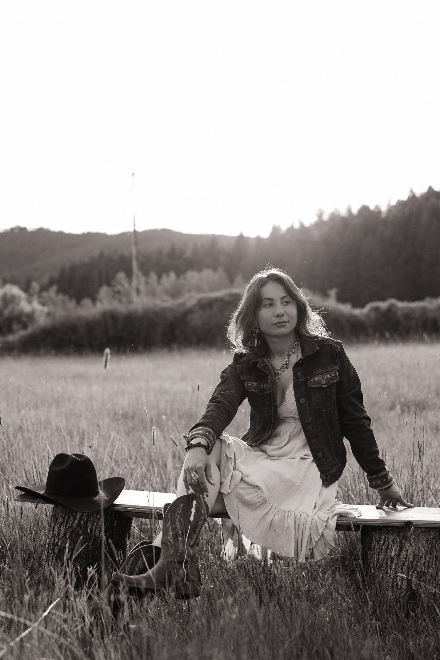 A person lying in a grassy meadow with mountains and trees in the background.