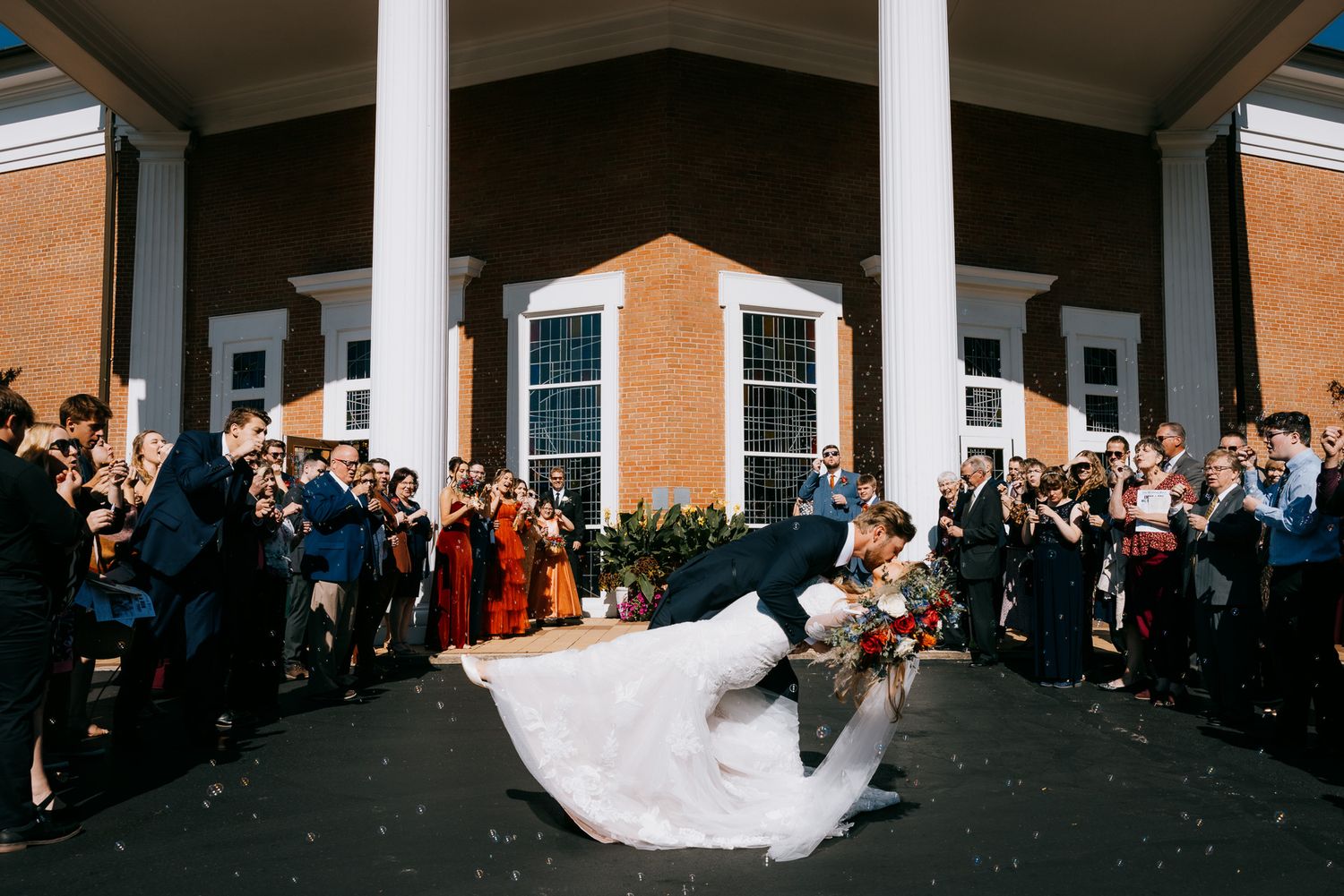 Epic just-married kiss outside a grand venue, joyful and cinematic, by Cleveland wedding photographer Swanky Bolt Studios.