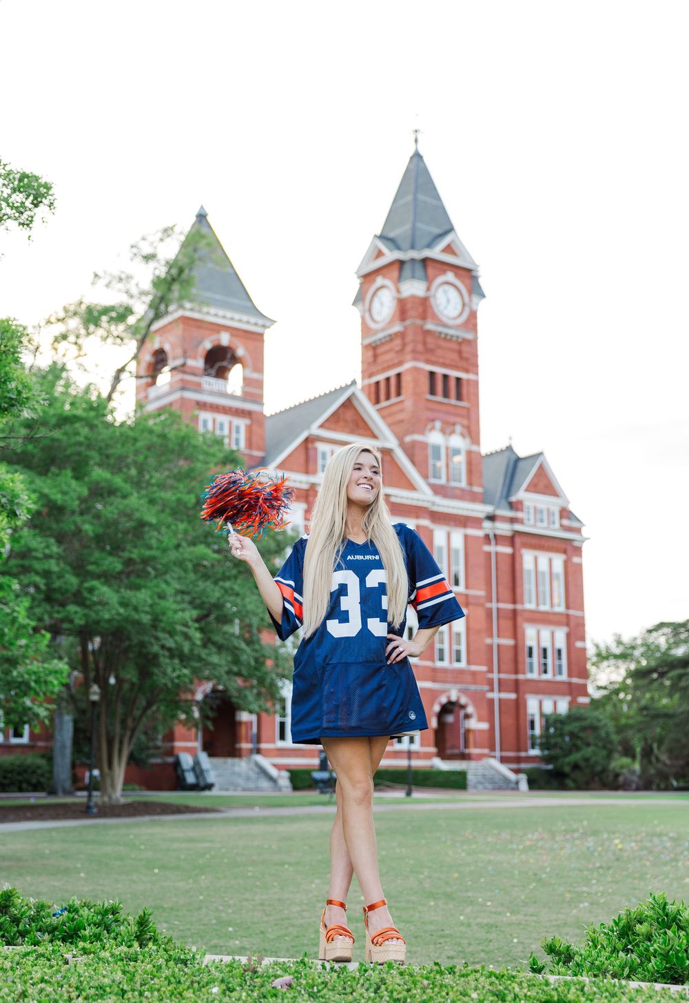 A graduation photo at Samford University featuring Auburn football jersey #33 and red flowers in front of historic buildings.
