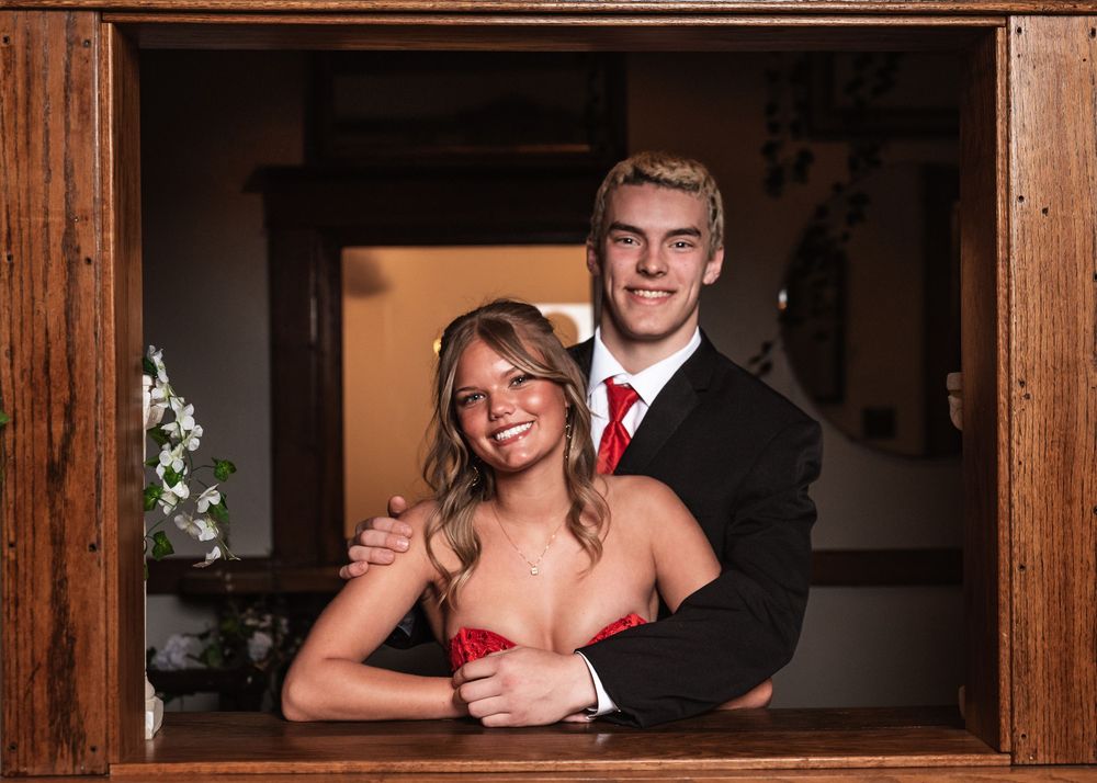 Formal portrait of a couple in evening attire posing together in an elegant wooden frame.