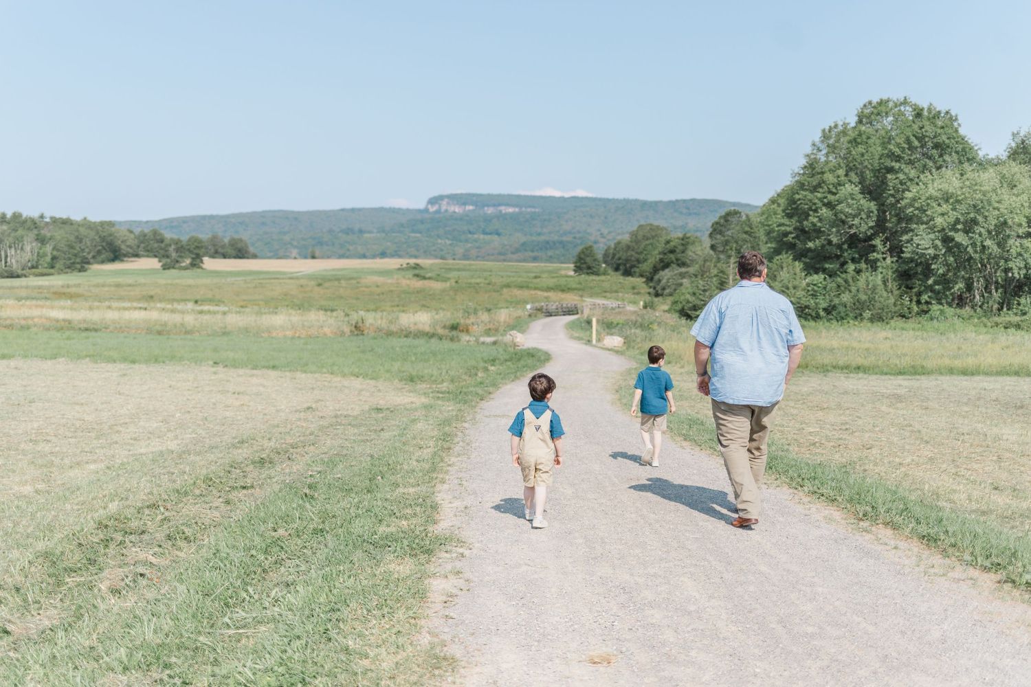 Father and sons walking on a path towards mohonk mountain in new paltz, NY during a family session.