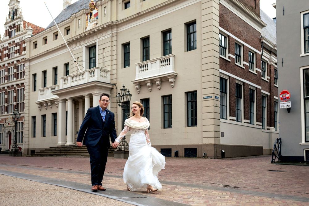 Winterbruiloft in Deventer: bruidspaar loopt hand in hand voor het stadhuis na de huwelijksceremonie