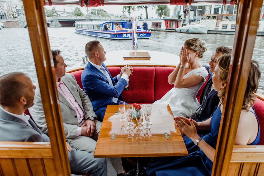 Trouwreportage op de grachten van Amsterdam met bruidspaar in salonboot en champagne