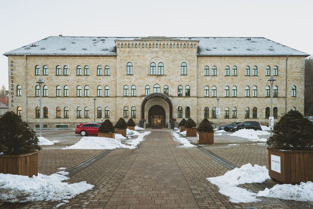 Historic stone building with arched entrance surrounded by snow covered grounds.