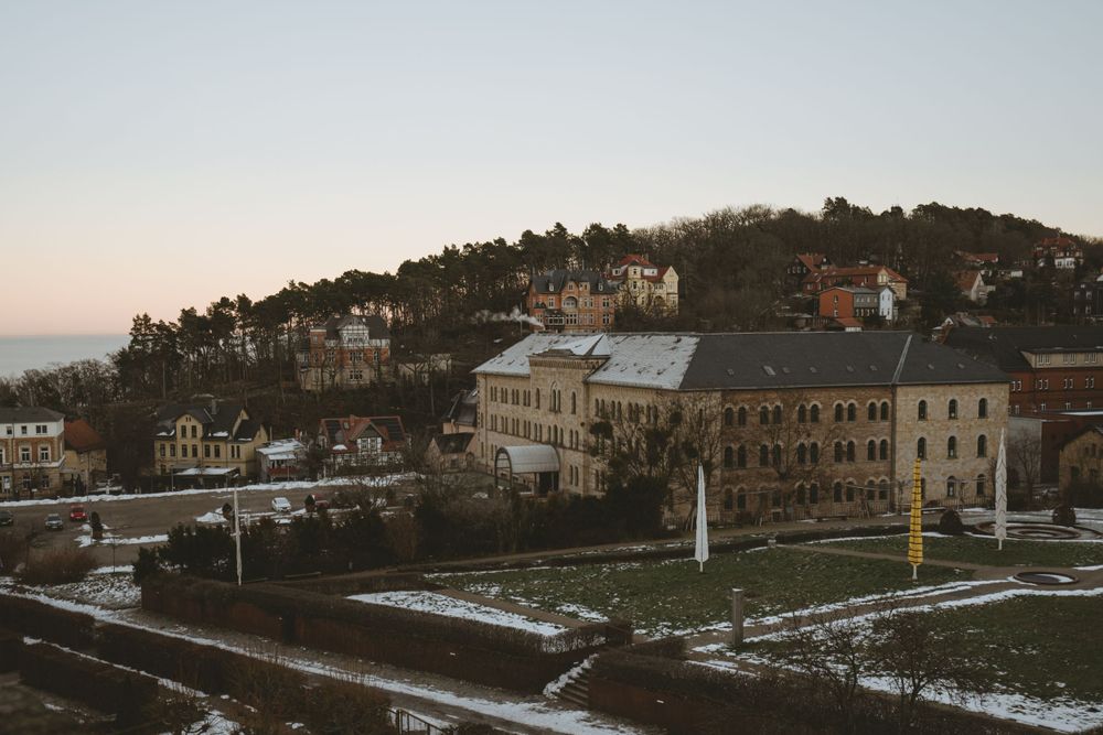 Hillside view of historic buildings and town landscape at dusk with snow patches visible.