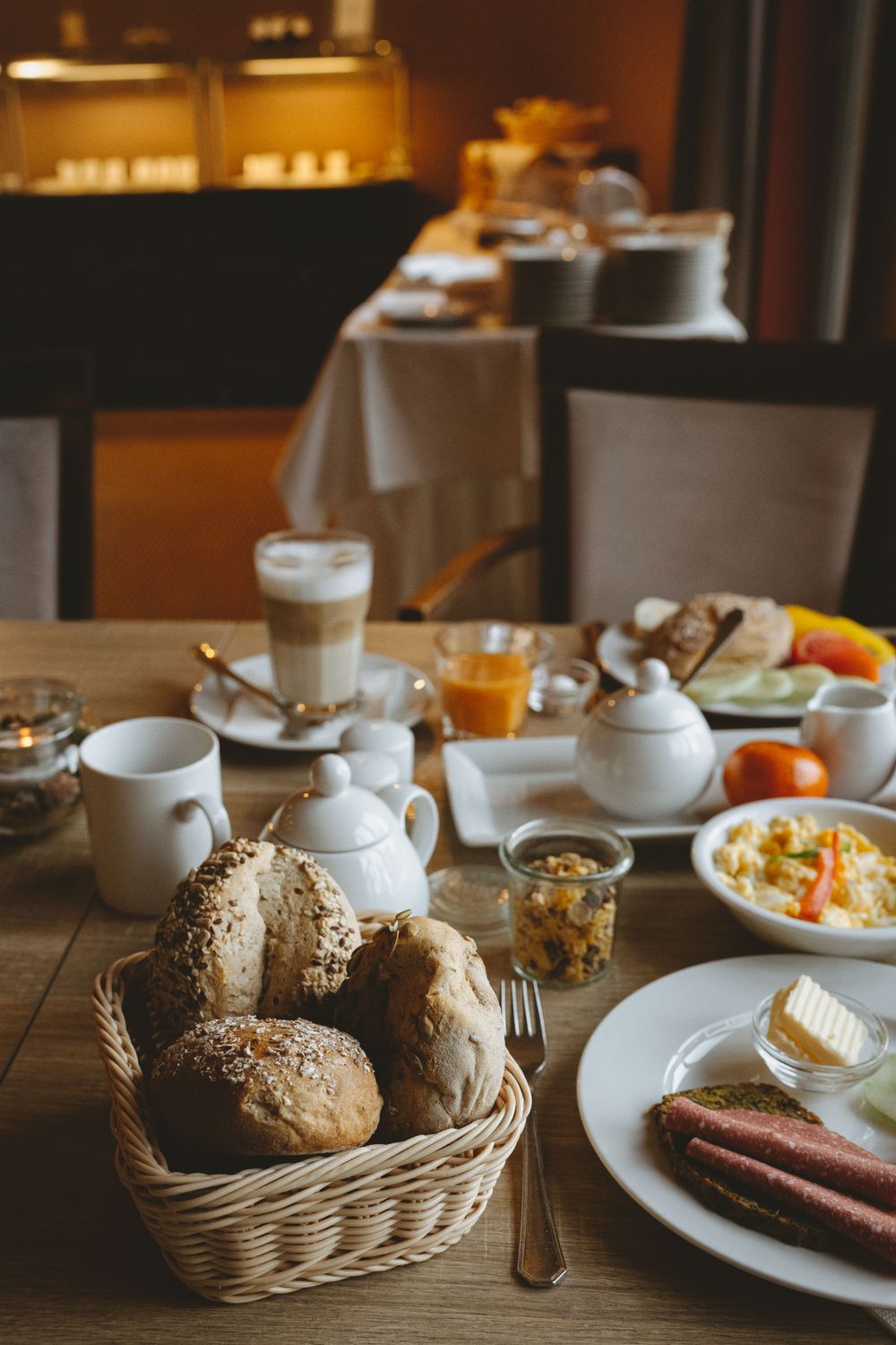 Luxurious hotel breakfast spread with fresh bread, pastries, coffee and orange juice.