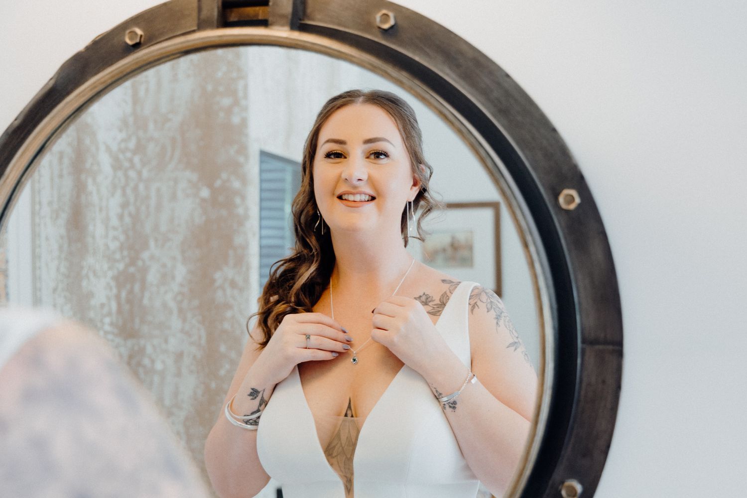 A bride in an elegant white dress looks at her reflection, captured by Apertured Media Auckland Wedding Photographer.