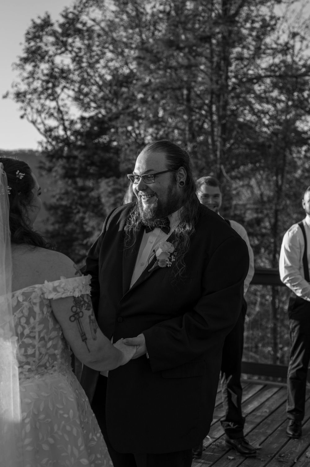 Black and white photo of joyful wedding ceremony moment on outdoor deck.