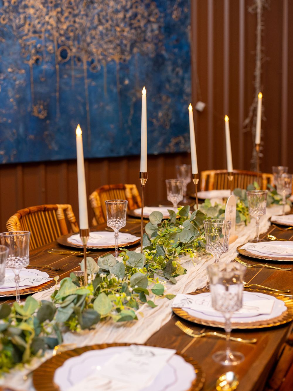 Elegant wedding reception table setting with taper candles and eucalyptus garland runner.