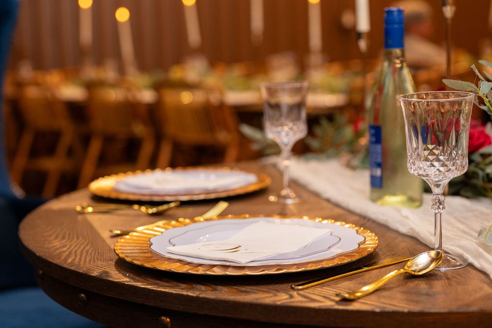 Elegant place settings with gold chargers and crystal glassware at a wedding reception.