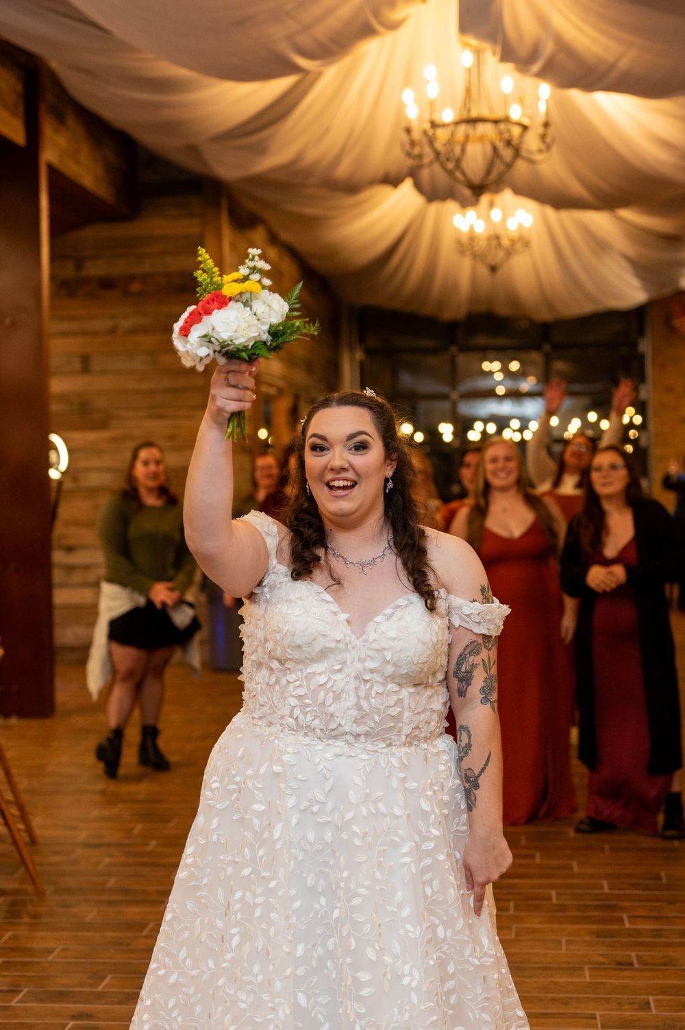 Joyful wedding celebration moment in a rustic venue with draped fabric ceiling and chandelier.