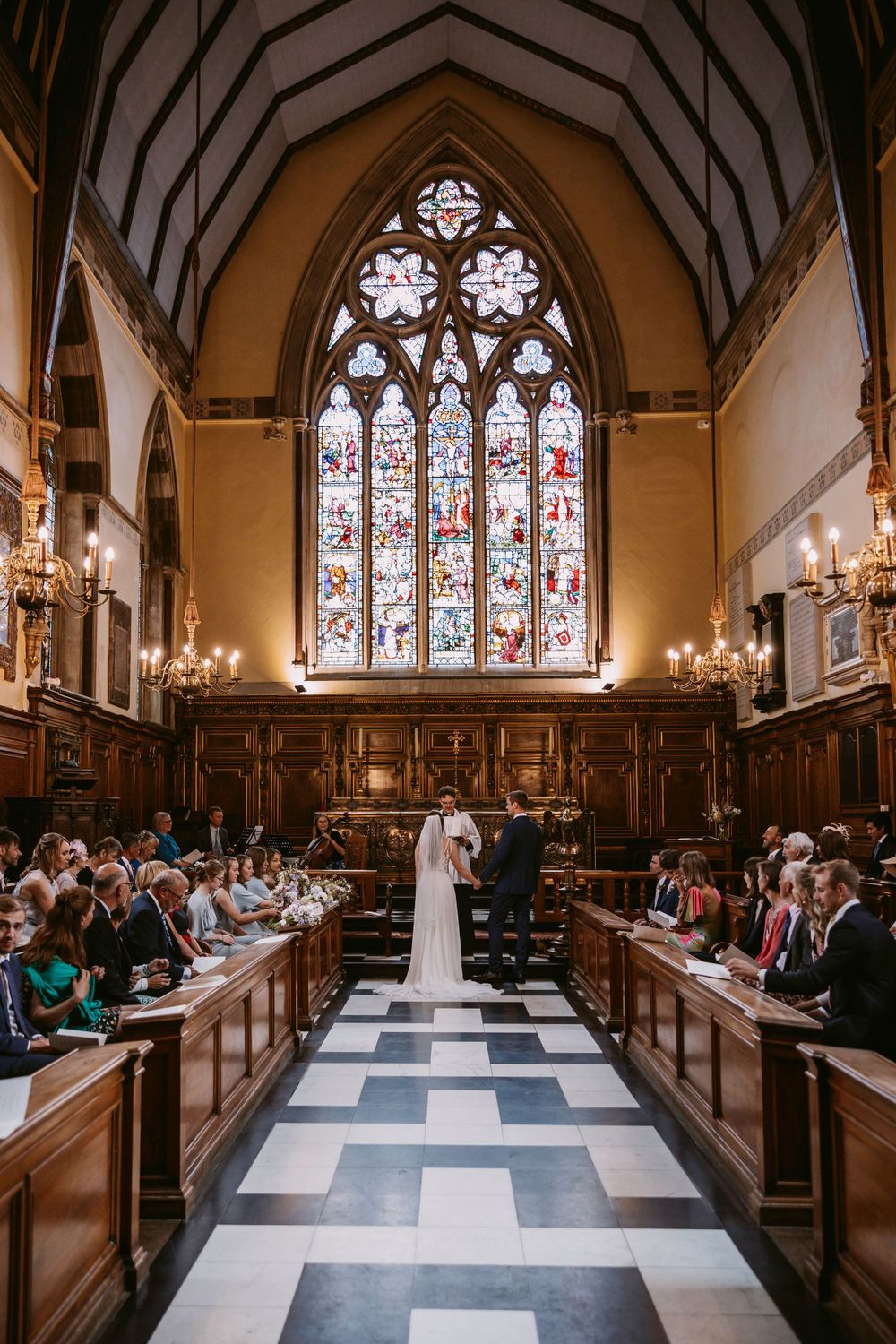Traditional chapel wedding with stained glass window and checkerboard aisle at Balliol College, Oxford