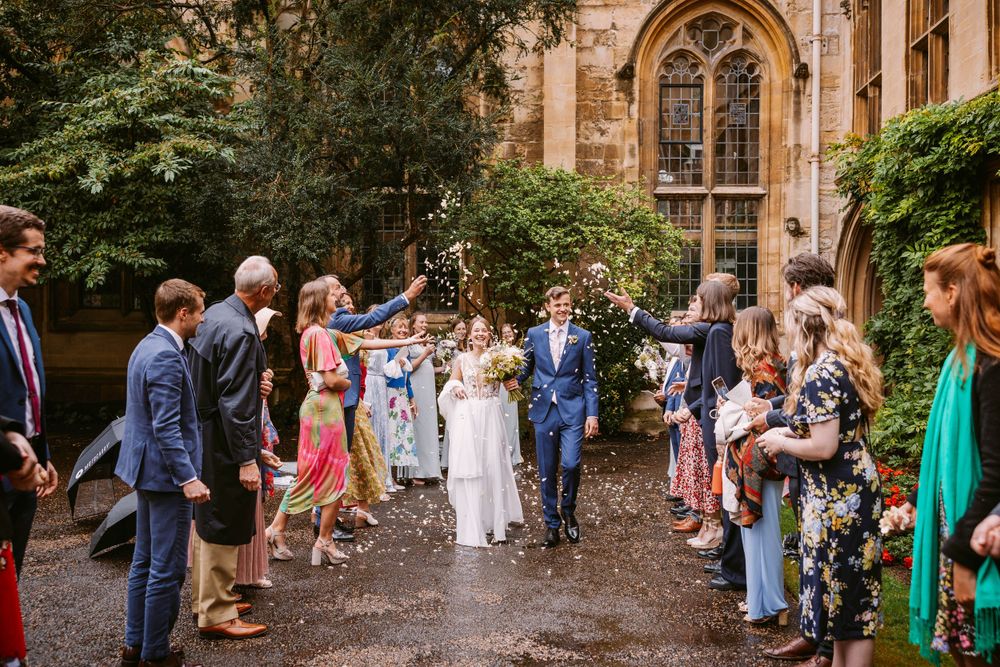 Wedding party celebrates with confetti toss in ivy-covered courtyard at Balliol College, Oxford