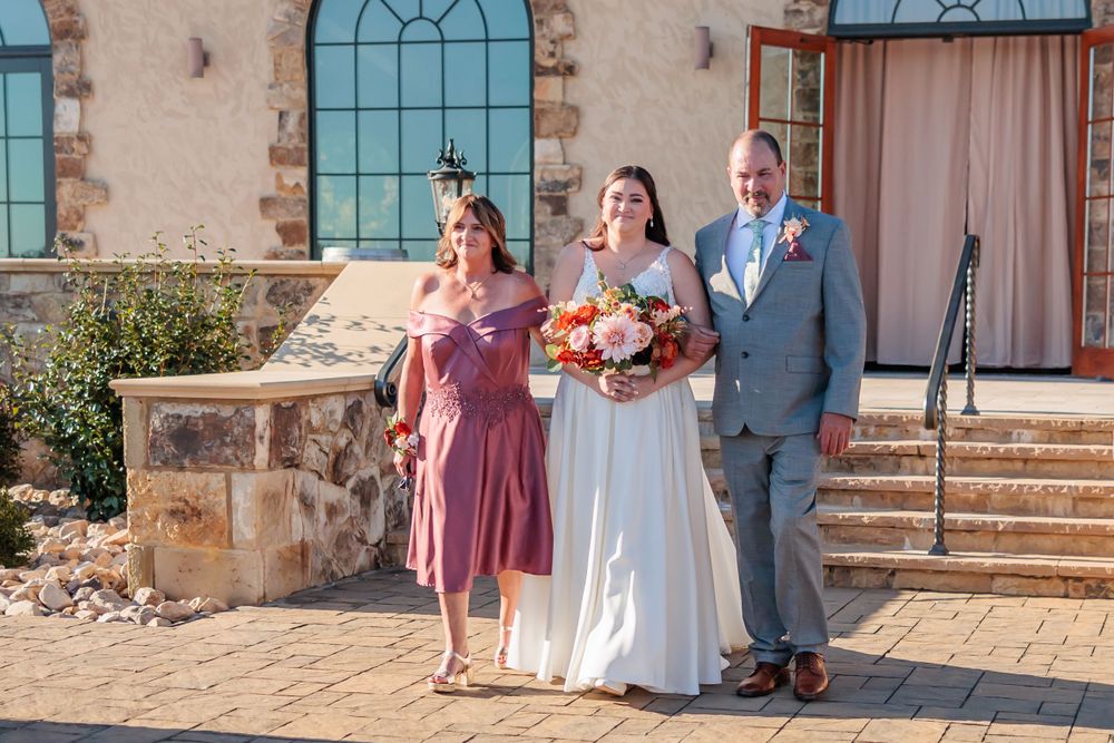 A small wedding party poses on the steps of a Mediterranean-style building.