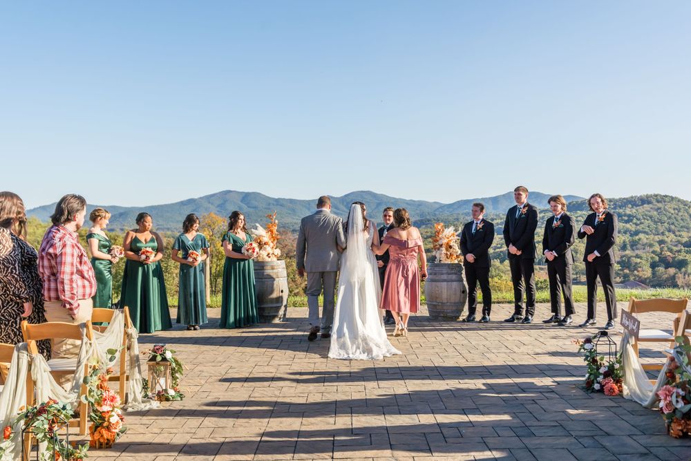 A scenic mountain wedding ceremony with wedding party members in green and pink dresses.