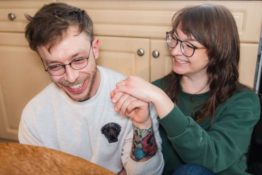 Couple laughs together while holding hands in kitchen.