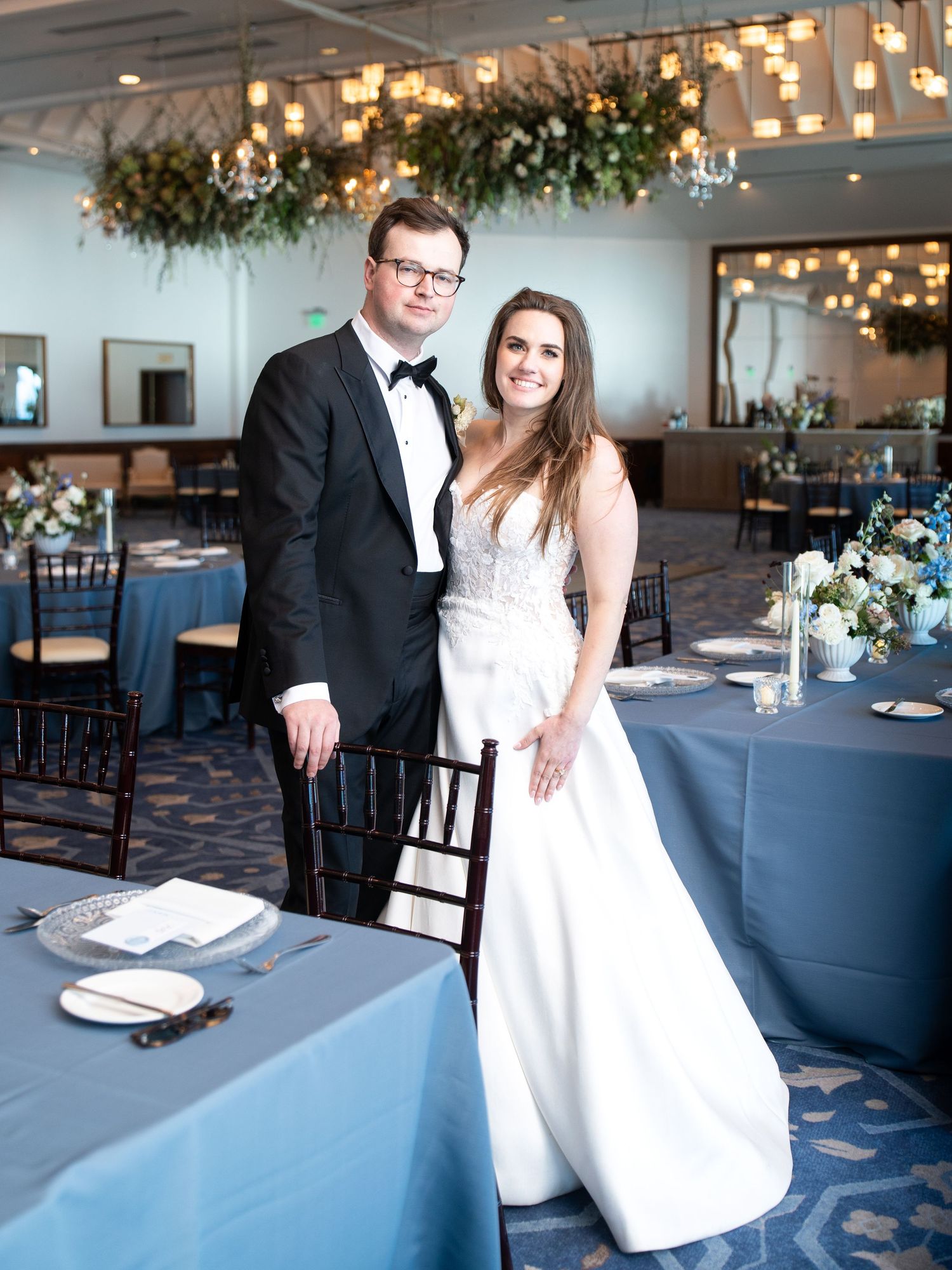 Newlyweds pose in the Hyatt Regency Tahoe ballroom with blue tablecloths and botanical decor during their elegant celebration.