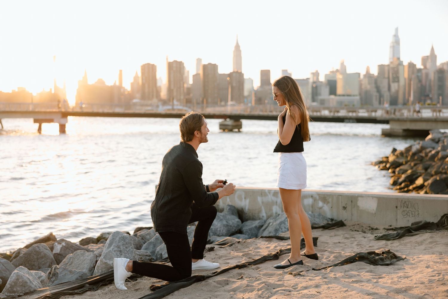 A couple’s proposal moment with the New York City skyline and the Hudson River in the background, capturing love against an iconic urban lan