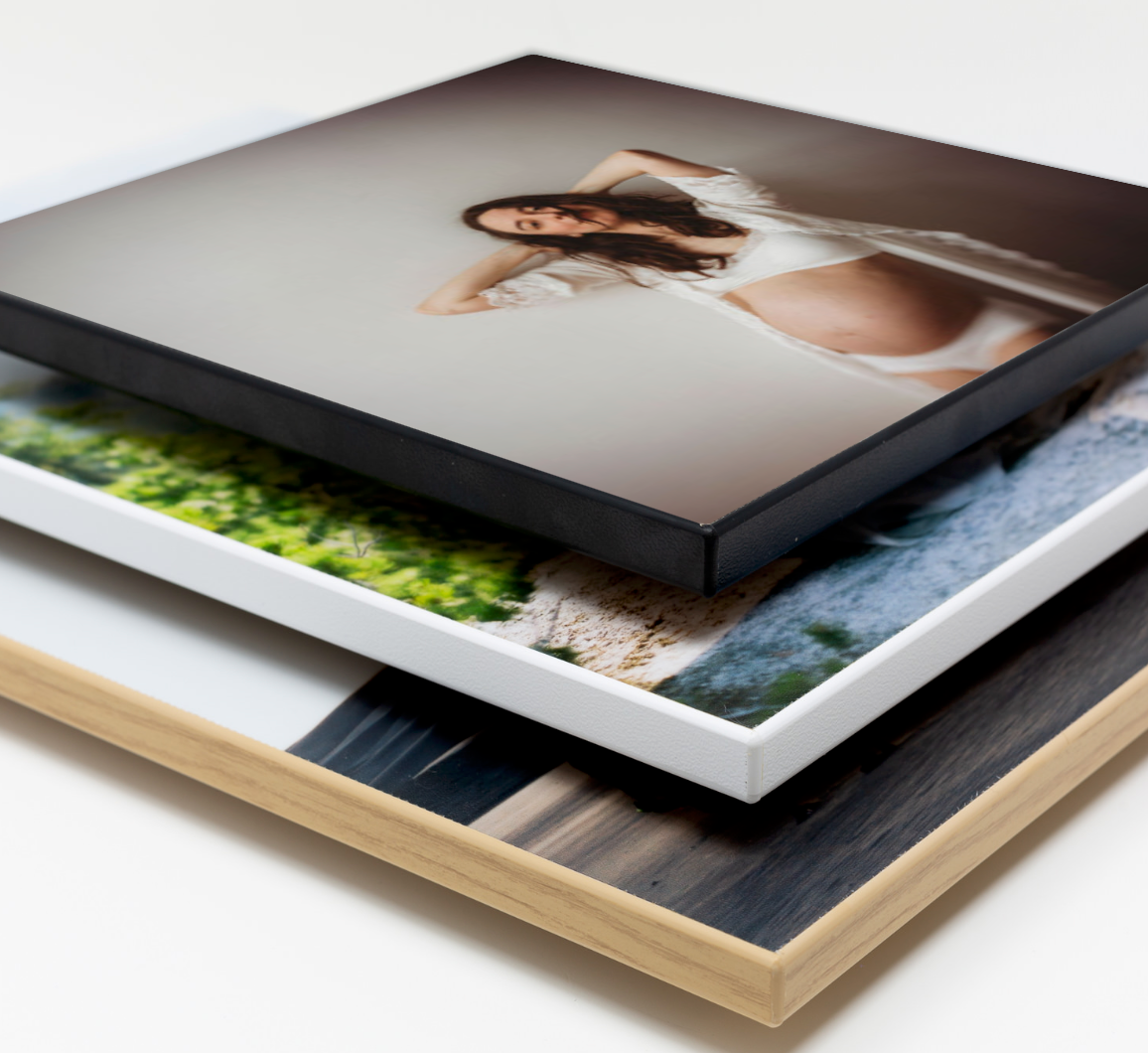 Stack of professional photo prints on different materials showing mounted photographic artwork and wall display options.