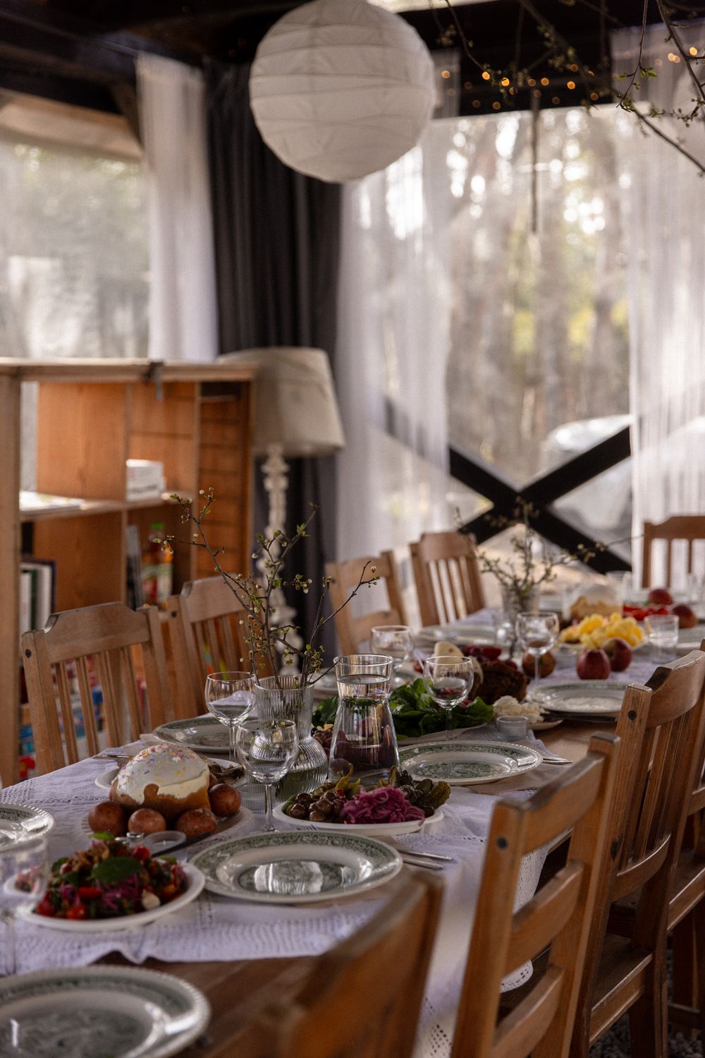 Elegant dining table set for a festive meal with glassware, fresh fruits, and floral centerpieces in a cozy rustic room.