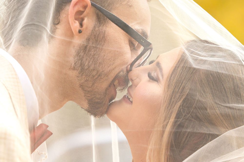 A romantic wedding photo of a couple sharing a tender kiss under a flowing white veil taken by fresno photographer.