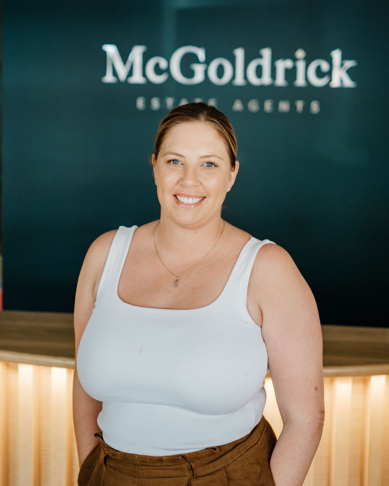 Smiling bearded man in gray shirt standing in front of McGoldrick Establishments sign.