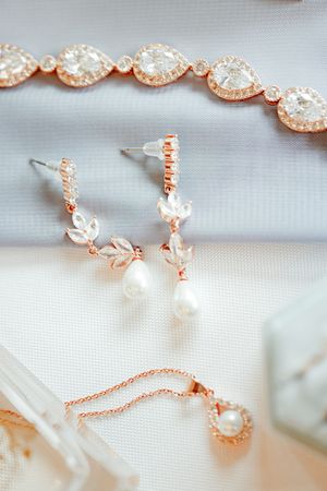 Rose gold bridal jewelry set featuring crystal bracelet, pearl drop earrings, and delicate pendant necklace.