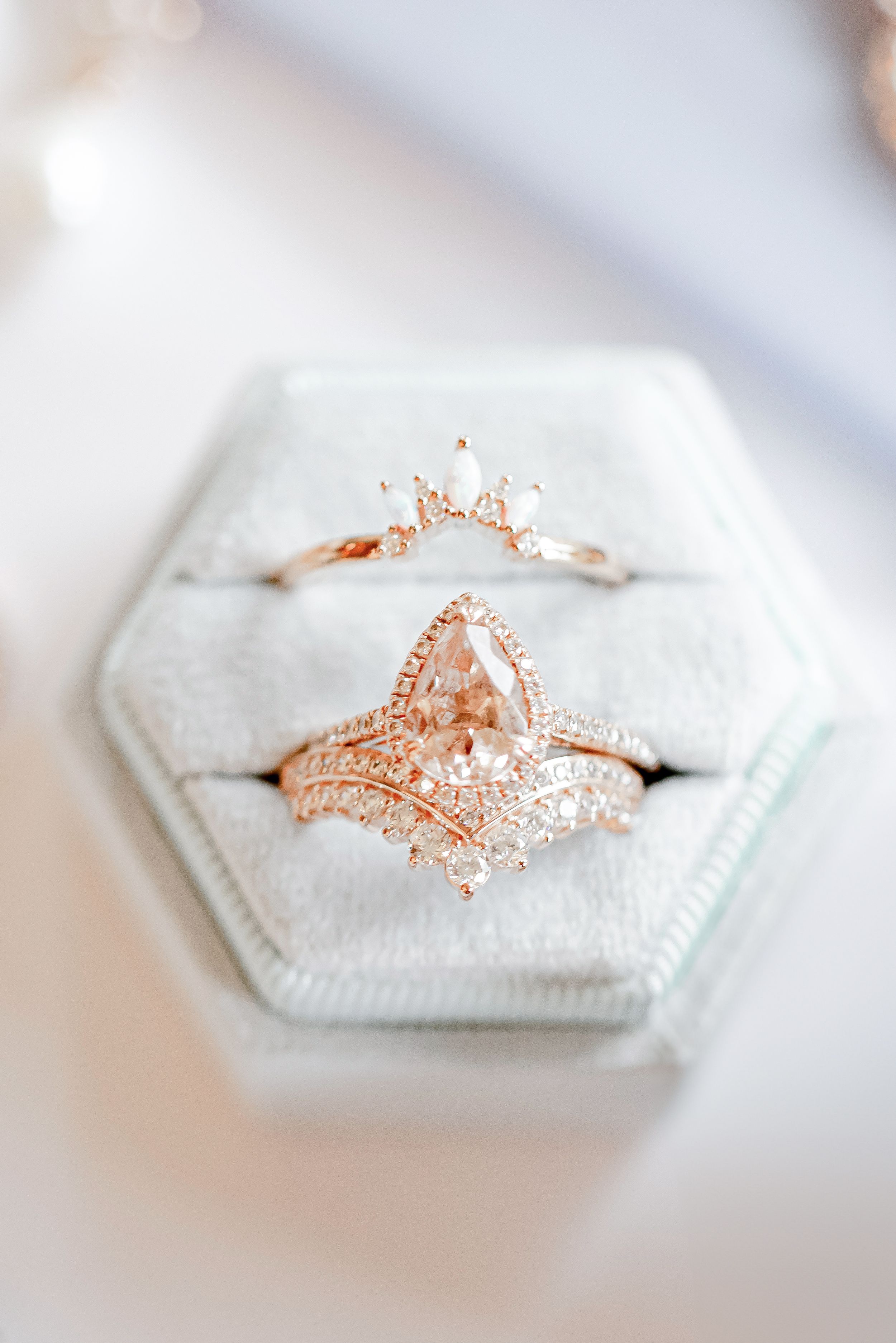 Rose gold pear diamond engagement ring with halo and chevron wedding band displayed in a hexagon velvet ring box.