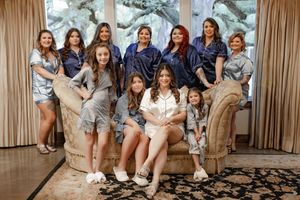 Bride and bridesmaids in matching satin robes posing together in elegant room before wedding ceremony.