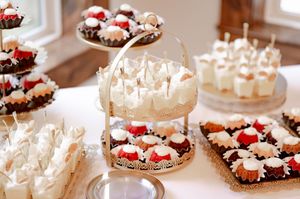 Elegant wedding dessert table featuring cupcakes with white frosting, strawberry toppings, and tiered display stands.