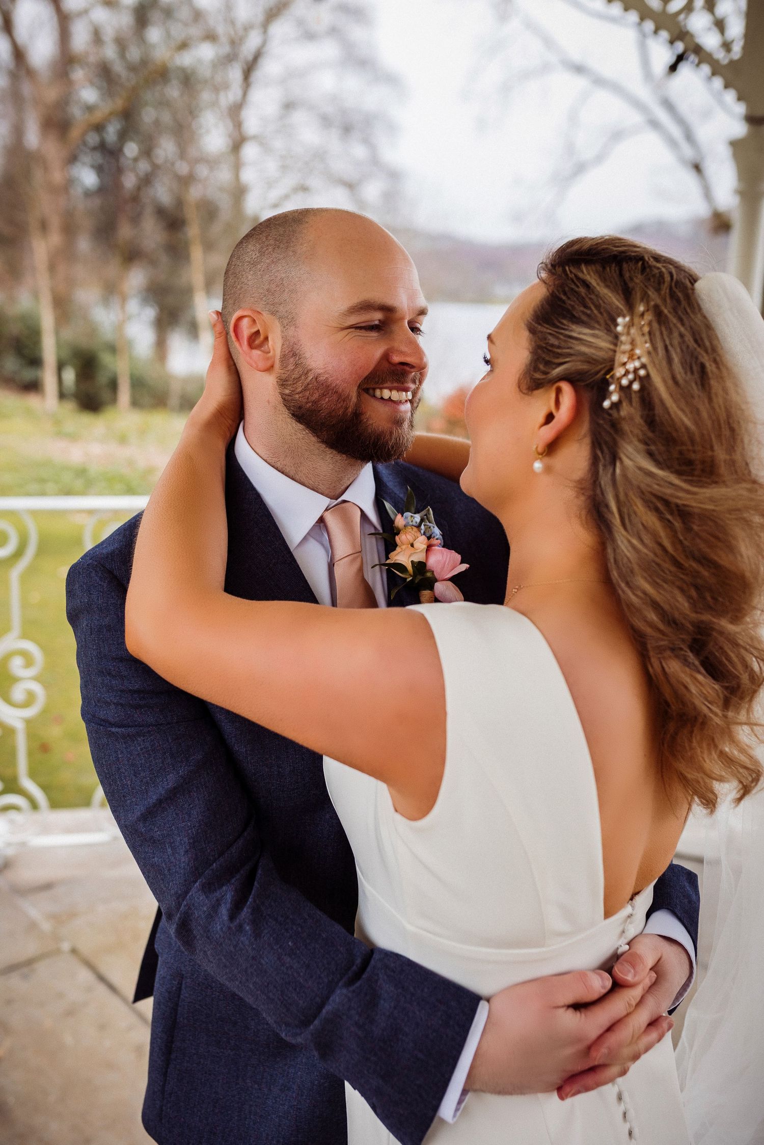 Bride and groom share a romantic embrace under the gazebo with string lights near the lake at Storrs Hall