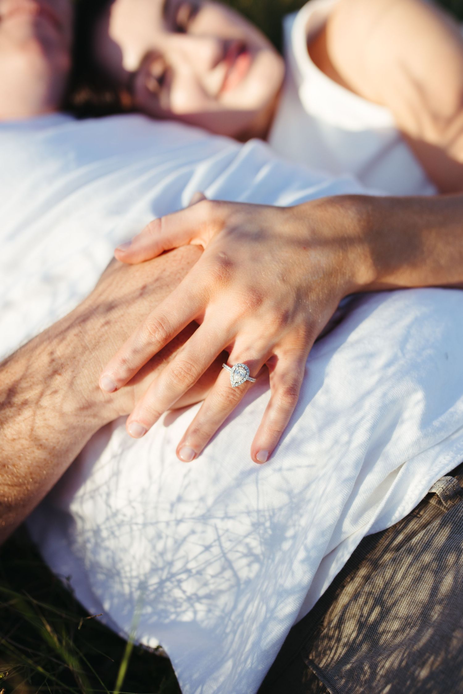 closeup of engagement ring with couple laying in the grass during Muswellbrook NSW engagement shoot