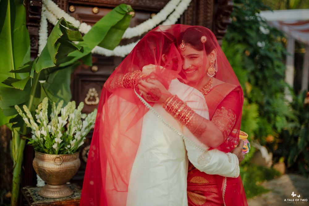 Indian bride in red saree sharing emotional hug during traditional wedding ceremony.