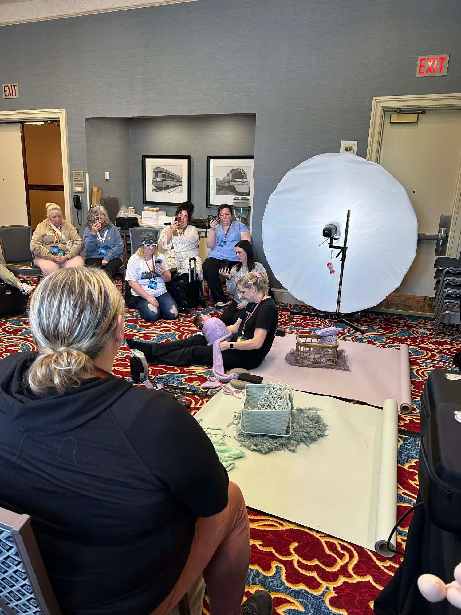 Group of women attending a photography workshop in a hotel conference room with a large reflector light.
