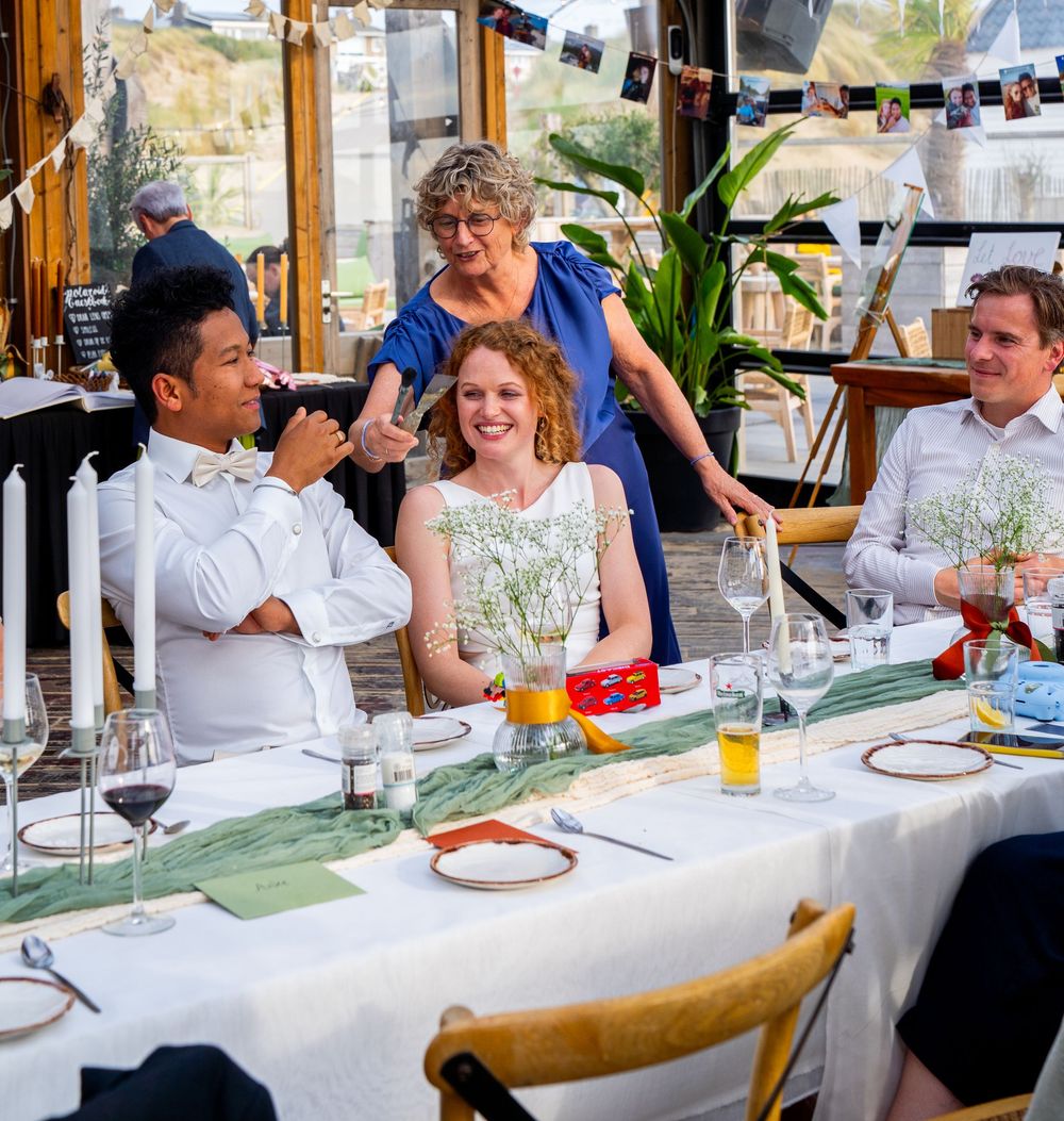 Bruiloftsgasten lachen en vieren samen feest aan een elegant gedekte tafel tijdens het receptiediner.