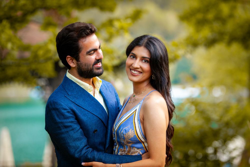 A happy couple in coordinating blue outfits embrace and smile in an outdoor setting.