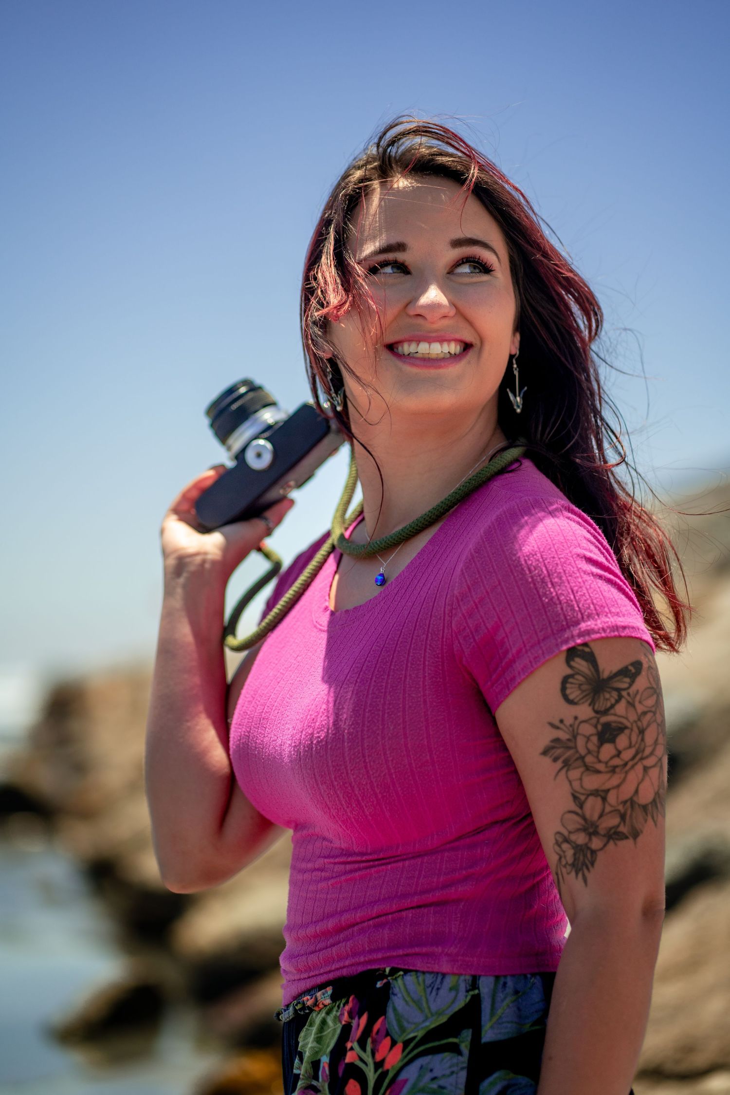 Southern California female beach photographer, looking up and smiling while holding film camera. Oceanside, CA